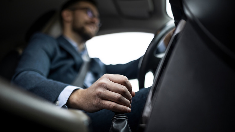 Close-up of driver shifting manual transmission, photo taken from passenger footwell