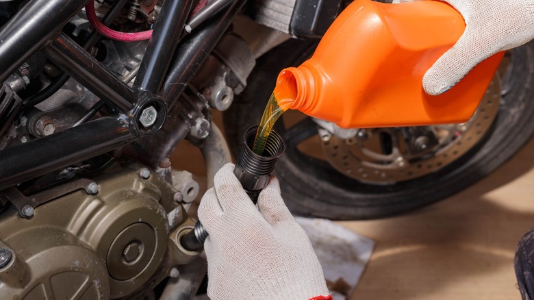 Adding oil to a motorcycle engine.