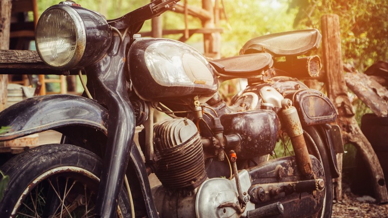 An old motorcycle parked against a wooden railing.