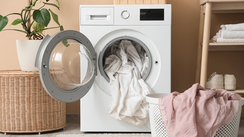 Washing machine with open drum in laundry room.