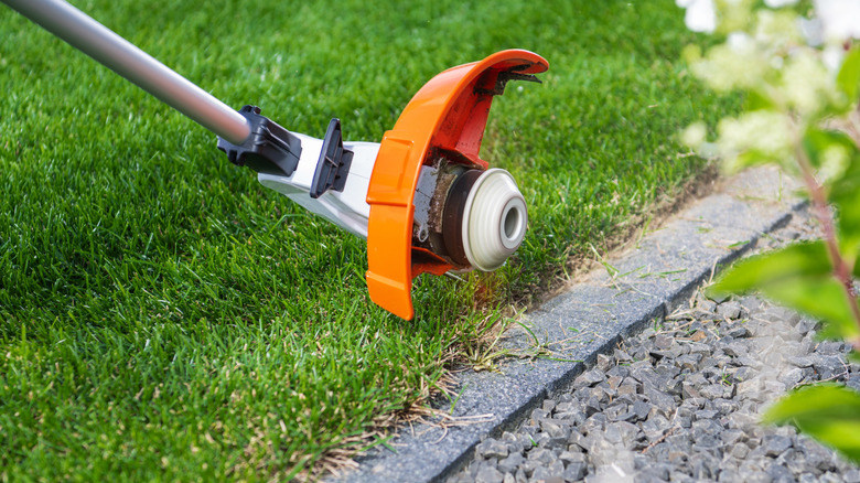 Weed eater edging a gravel sidewalk