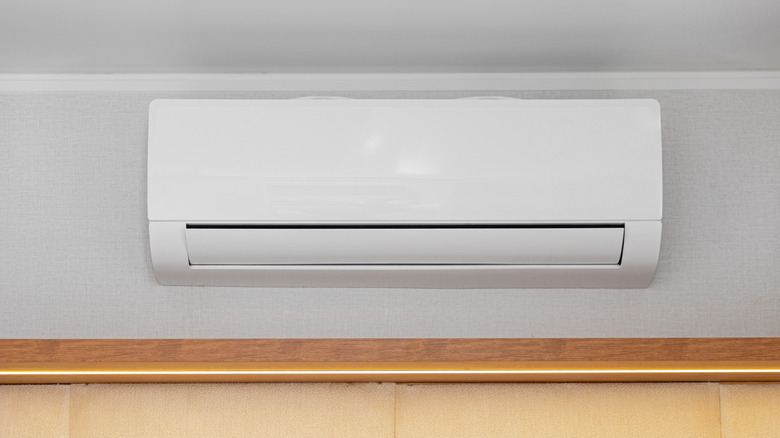 White air conditioner mini split unit mounted at wall in room