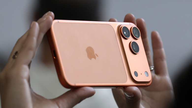 A person holding an orange color iPhone 17 Pro
