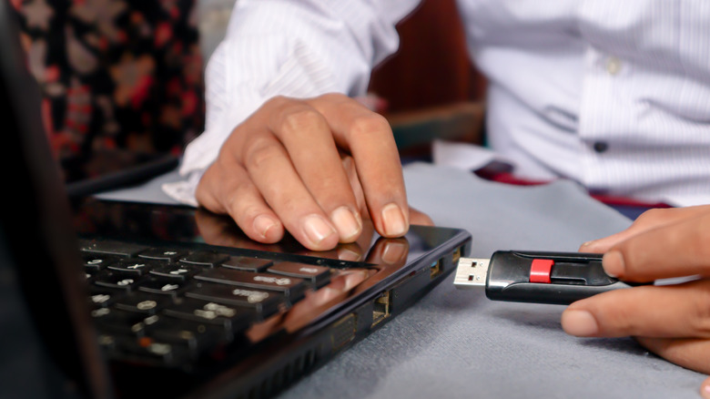 A person plugging a USB drive into a laptop