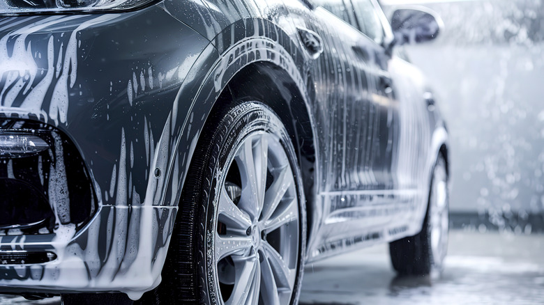 black car in car wash with soap and water