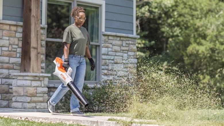 Person using Stihl blower to remove grass from their walkway