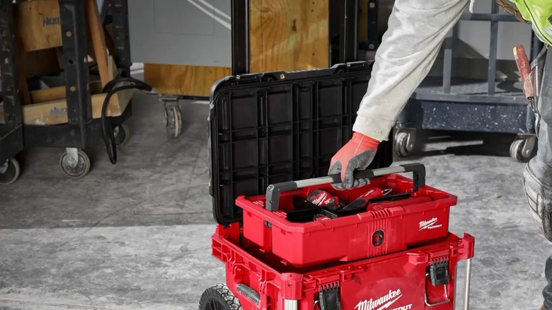 A worker retrieves tools from a Milwaukee Packout rolling toolbox