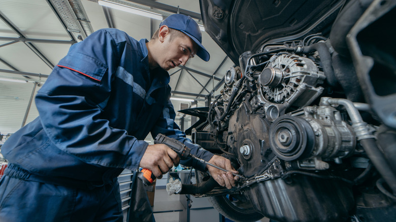 An auto mechanic repairing an engine