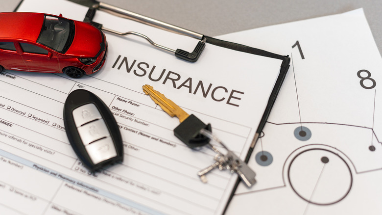 Top view of car insurance claim form with car key and car toy on desk.