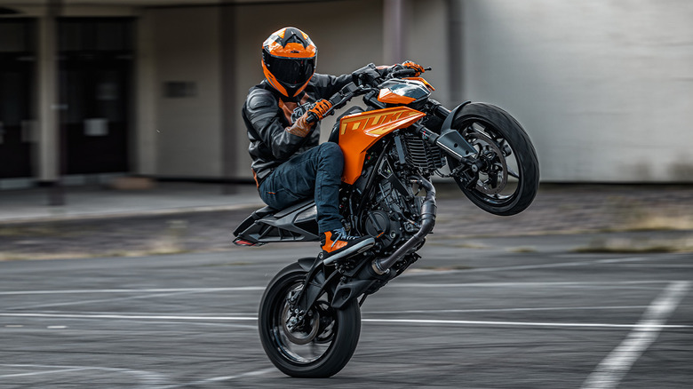 An action shot of an anonymous person doing a wheelie on the 2025 KTM Duke 250 motorcycle.