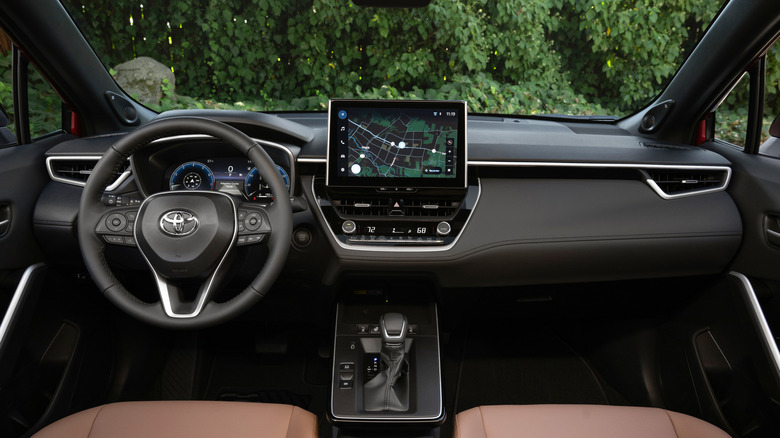 The interior of the latest Corolla Cross, tan leather seats, woods in the background