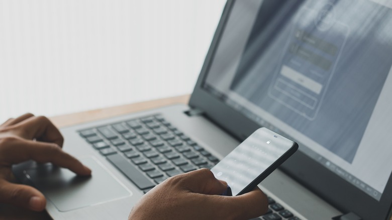 person unlocking laptop with phone