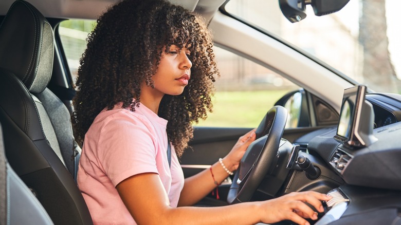 Woman in driver's seat pressing a dial
