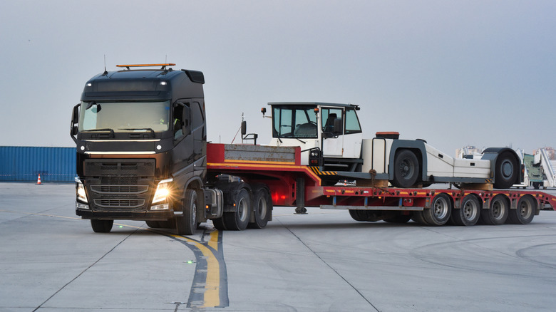 A European semi-truck carrying an aircraft tug on a flatbed trailer