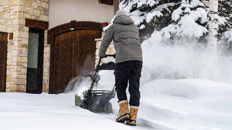 A single-stage snow blower in use to clear the path to the front door of a snowed-in home