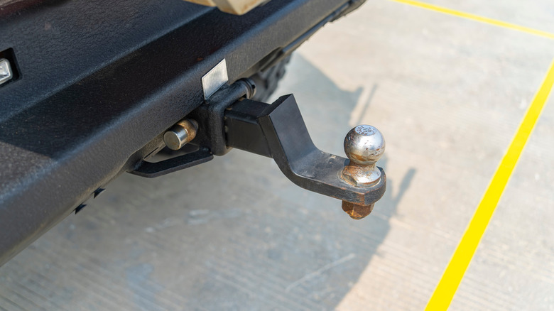 A close-up of a towing receiver, hitch mount and hitch ball on the back of a vehicle