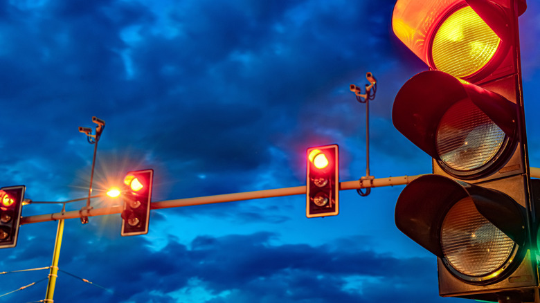 Four traffic lights, one in the foreground, against a cloudy sunset sky