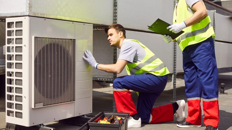 Two service people installing an HVAC.