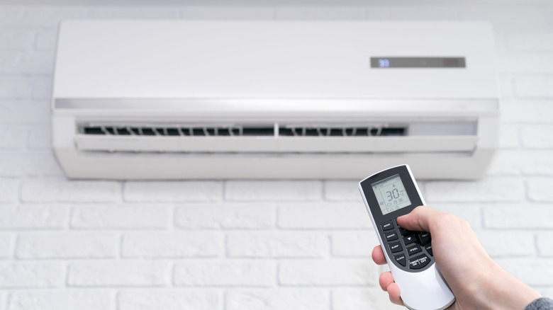 A person holding a remote adjusting an air conditioner.
