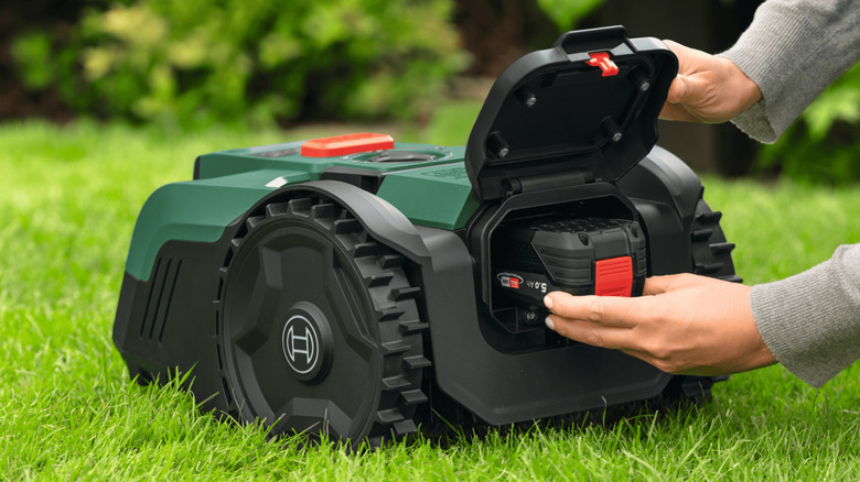 Person installing a battery in a Bosch Visimow robot mower