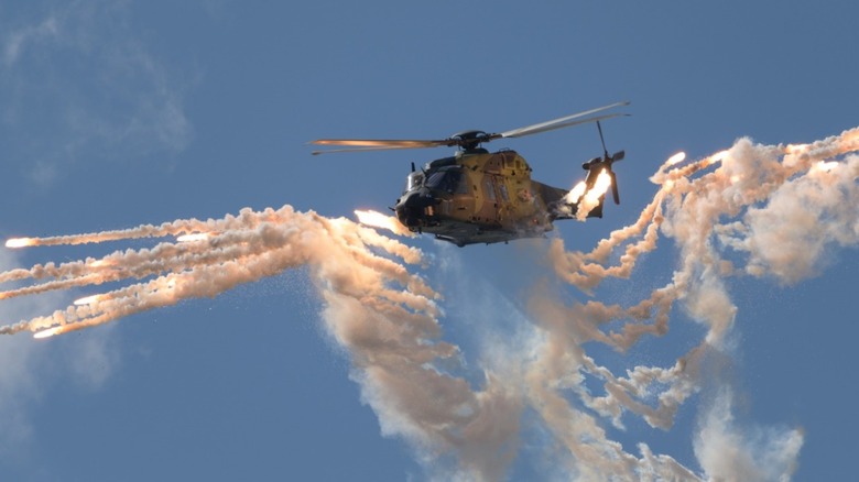 A military helicopter releasing chaff and flares
