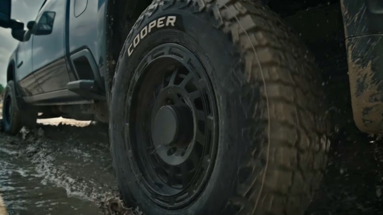 A Cooper tire driving through mud.