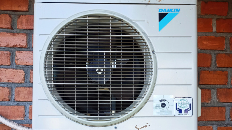 Wall-mounted Daikin outdoor AC unit against a red brick wall