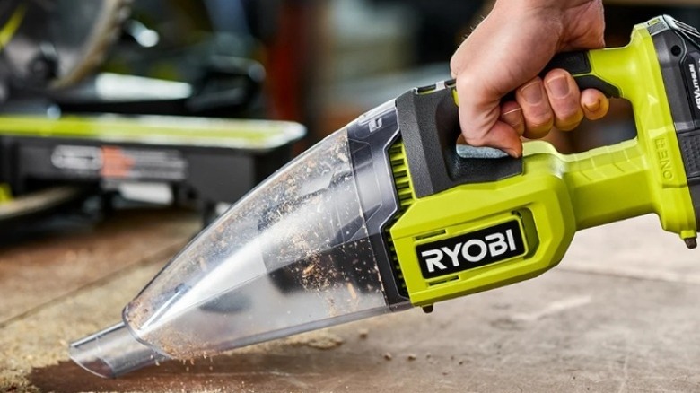 Ryobi brand hand vacuum cleaning sawdust from a workspace