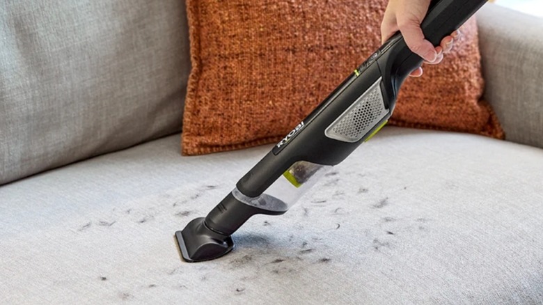 Handheld vacuum cleaning fur off beige furniture