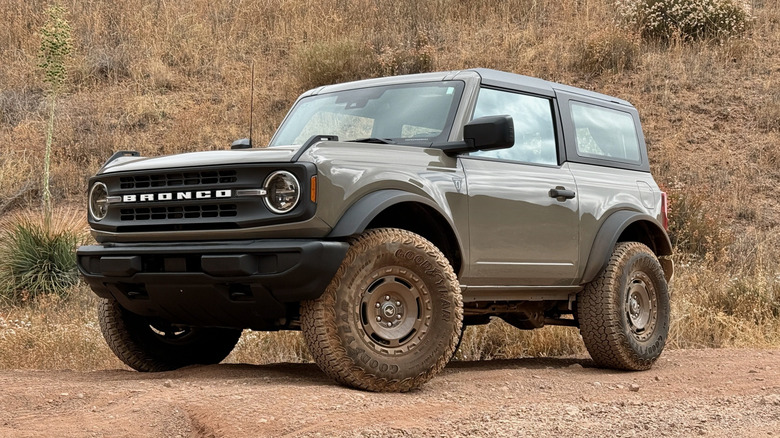 Marsh Gray Ford Bronco Sasquatch parked off-road in front of a brushy hillside