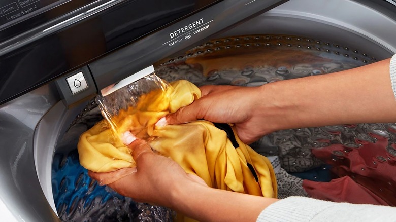 A person inspects clothes from a Whirlpool top-loader washing machine