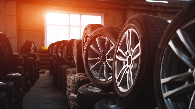 A bunch of tires and wheels standing upright with a bright sunset in the background