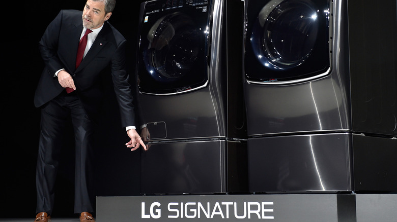 A presenter gesturing to two LG signature appliances on stage at a trade show