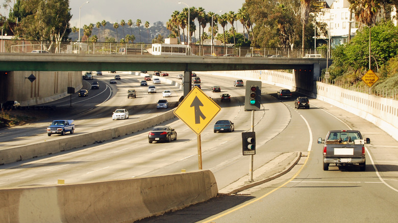 A busy roadway with a prominent merge traffic sign.