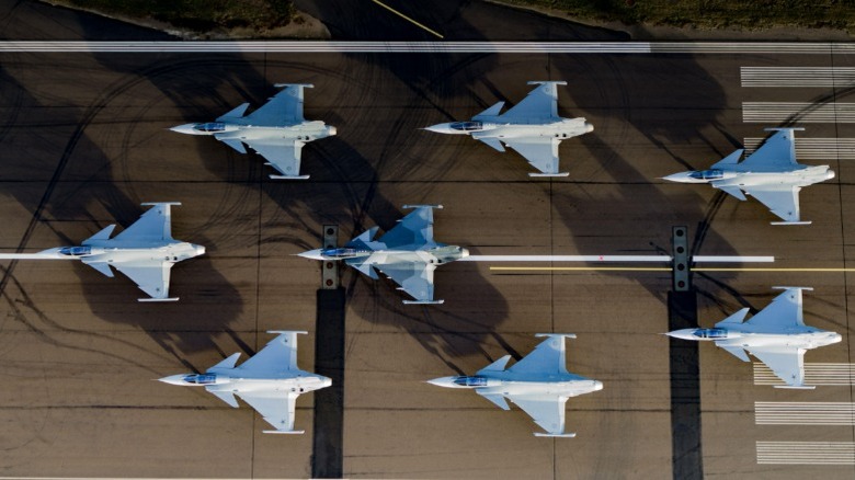Bird-eye view of eight Gripen Es sitting on a runway in formation.
