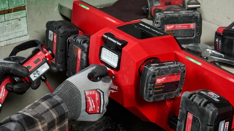 Gloved hands using a Milwaukee M18 and M12 Gangbox Rapid Charger