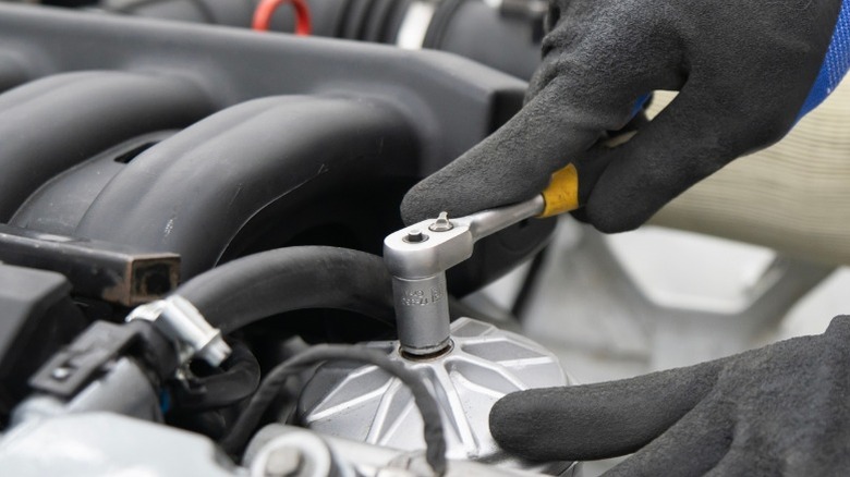 a person using a ratchet wrench on an automotive component