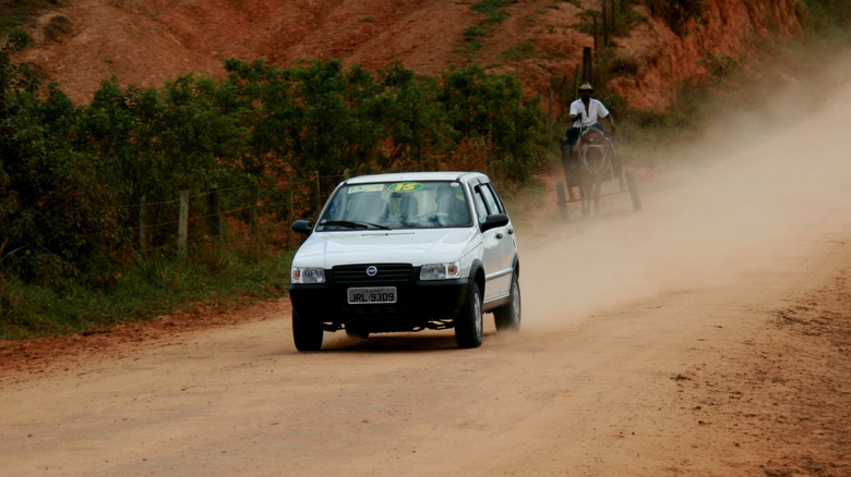 A compact car traveling on a dirt road