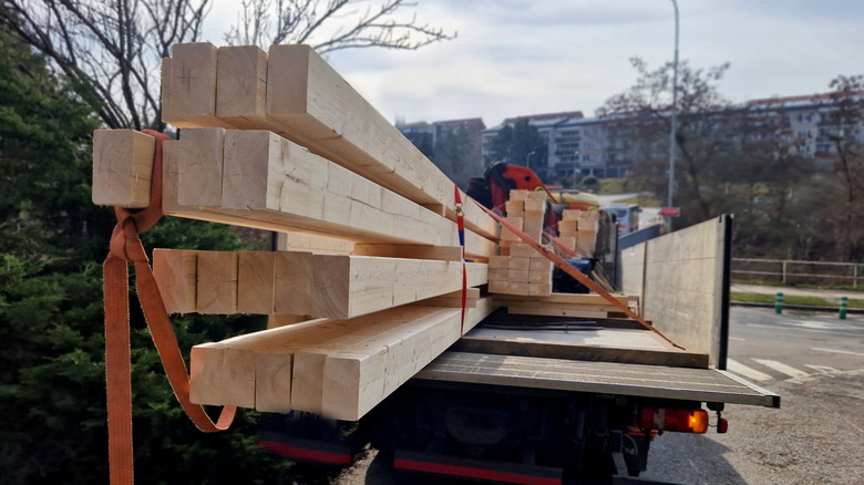A truck with a bundle of lumber hanging off the back.