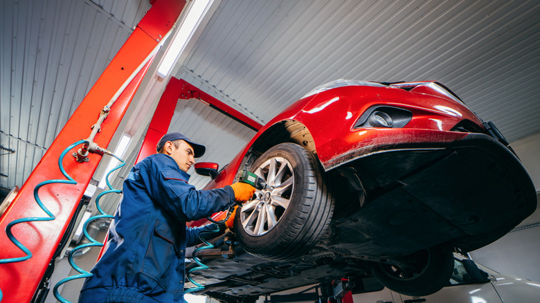 A man working under a car held off the floor by a lift