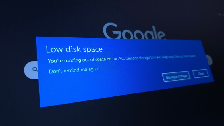 Low disk space warning on Windows 11 with Google open on a browser in the background