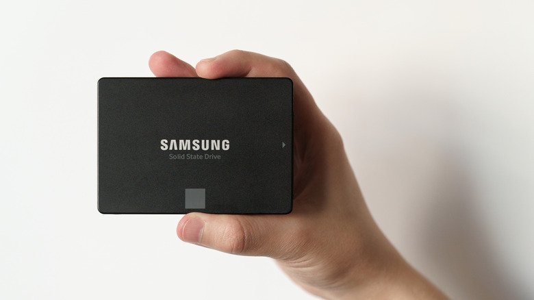 A hand holding a Samsung SSD against a white background