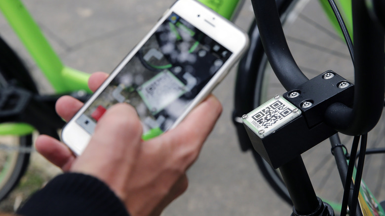 A man scanning the QR code on a bike from a city sharing service.