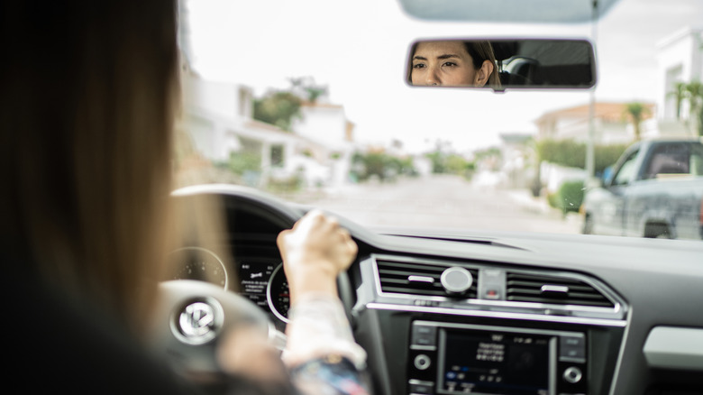 Driver's face reflected in rearview mirror.