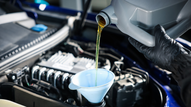 Mechanic pouring motor oil into a car engine.