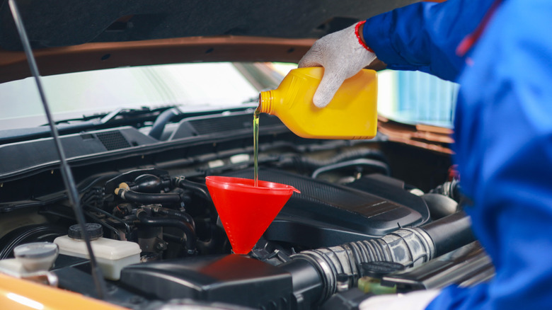 Mechanic pouring engine oil into car engine during an oil change