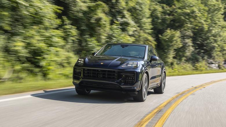 Front 3/4 dynamic shot of a blue 2025 Porsche Cayenne GTS driving a twisty road.