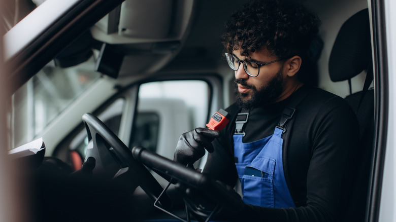 A mechanic performing vehicle diagnostic inside a van using an OBD-II scanner