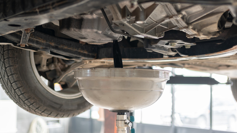 A raised car draining oil.