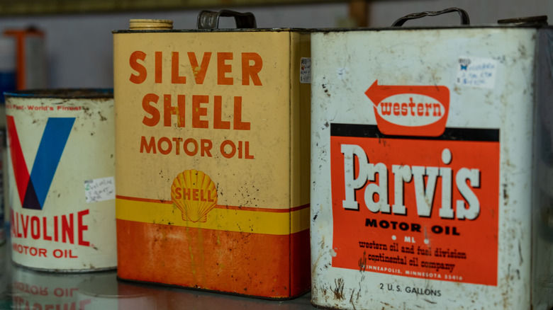 Three vintage motor oil cans Valvoline, Shell and Parvis brands on a glass shelf.